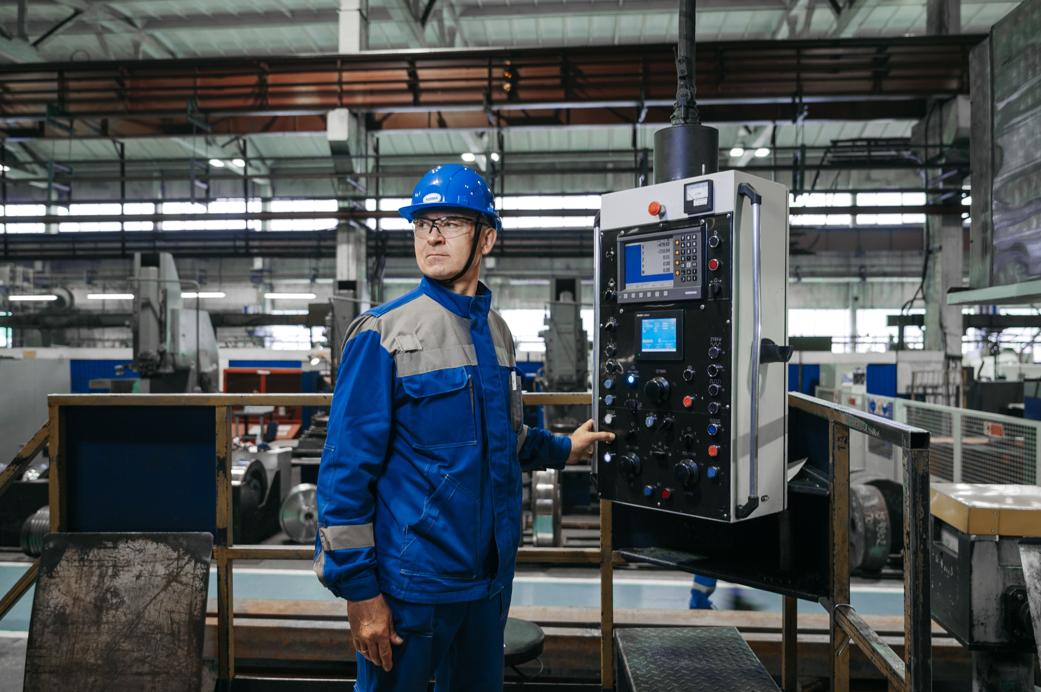 Factory worker in safety gear operating industrial machinery